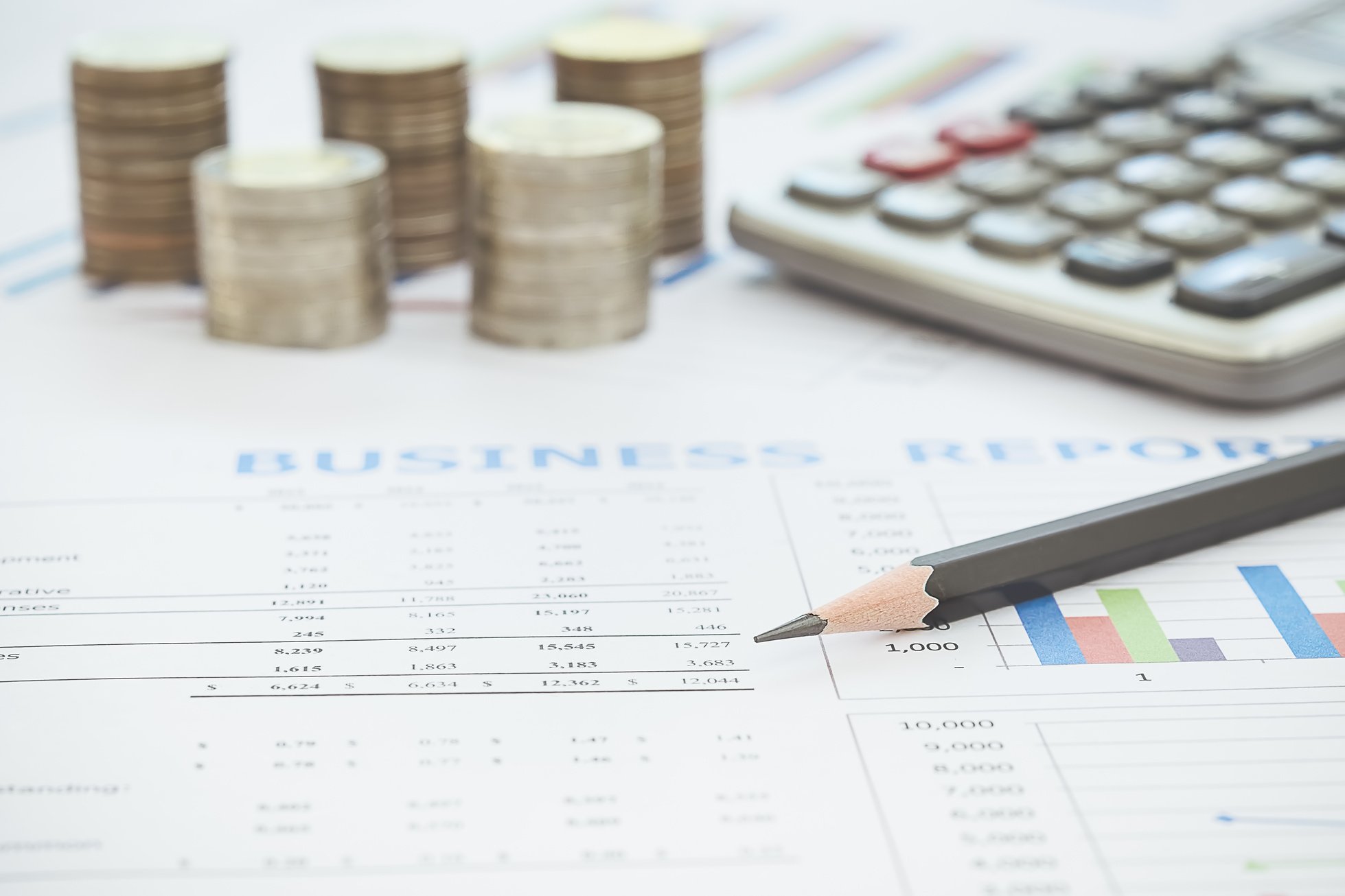 Stack of Coins, Calculator and Pencil on Business Report